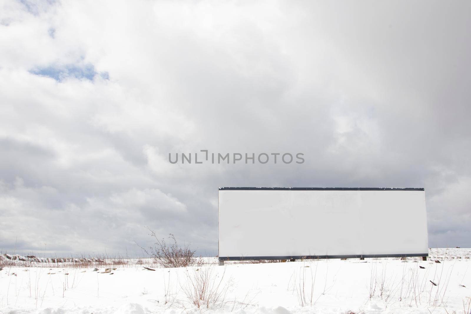  a white sign with copy space sits ready for billboard in a wide open winter meadow