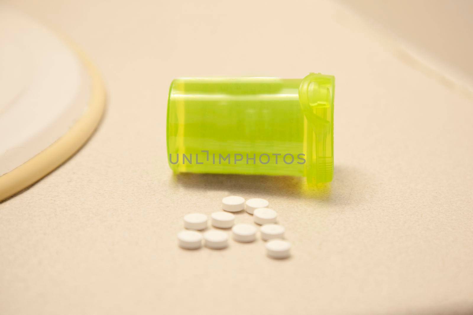 A handful of white pills on a counter in the bathroom with a bottle 