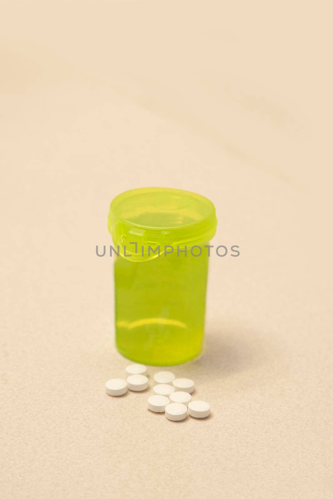 A yellow bottle of pills on the bathroom sink beside a handful of white medicine 