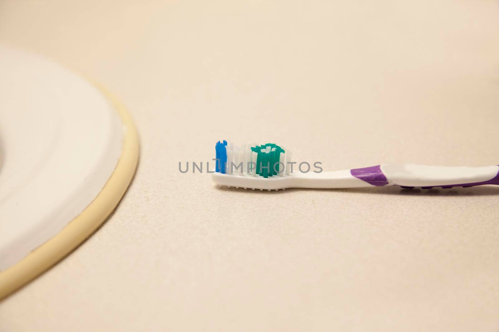 A white and purple toothbrush sits by the bathroom sink 