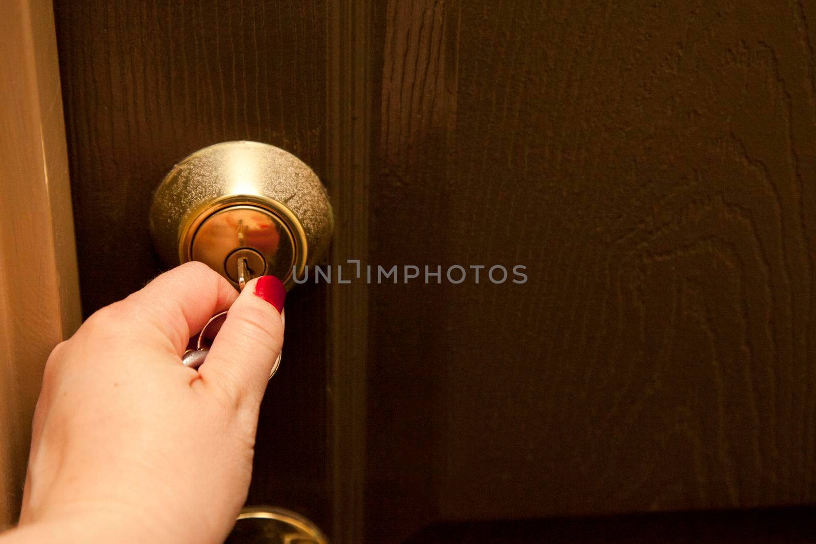 Hand inserts a key into the lock of a door