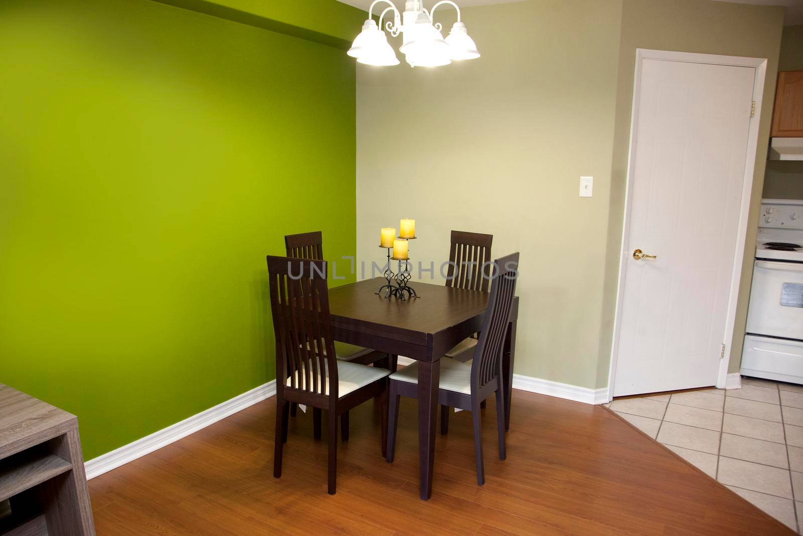 Green walls with a dark wood table and chair set for four in a kitchen or dining area of a home