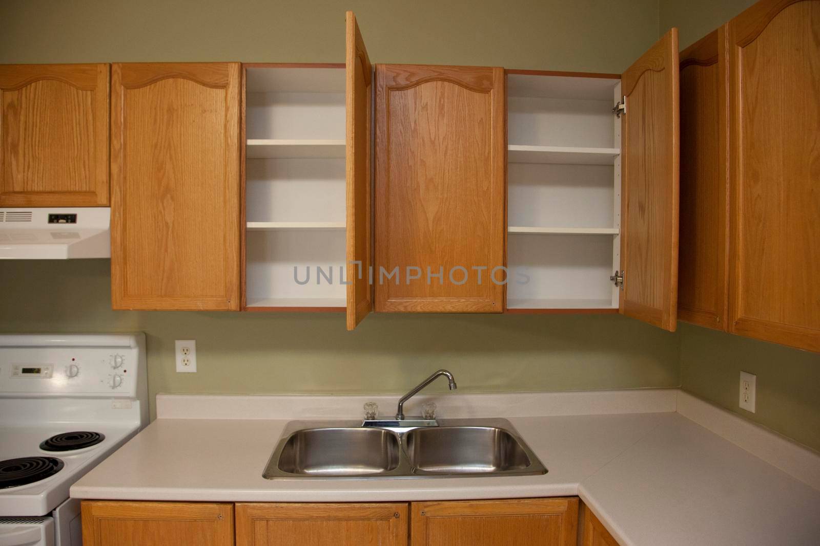 A small kitchen counter space with a sink and open, empty cupboards
