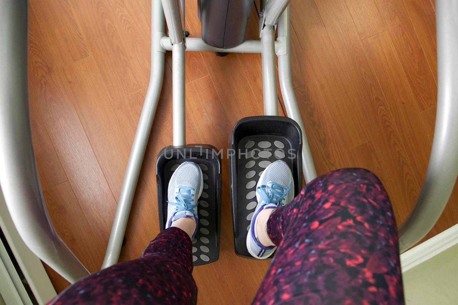 Point of view person exercising on elliptical machine at gym 