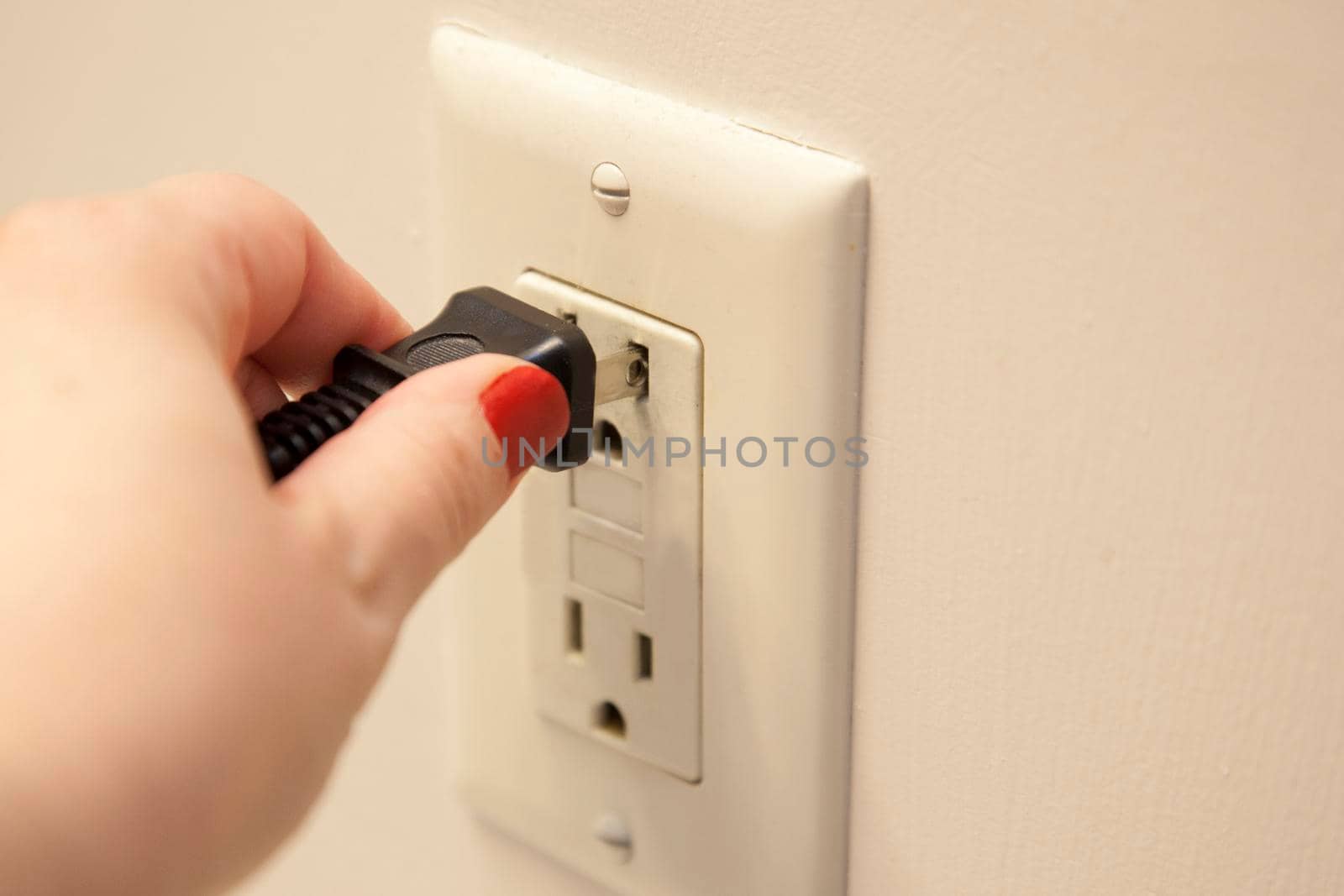 Hand plugging or unplugging a cord into an outlet