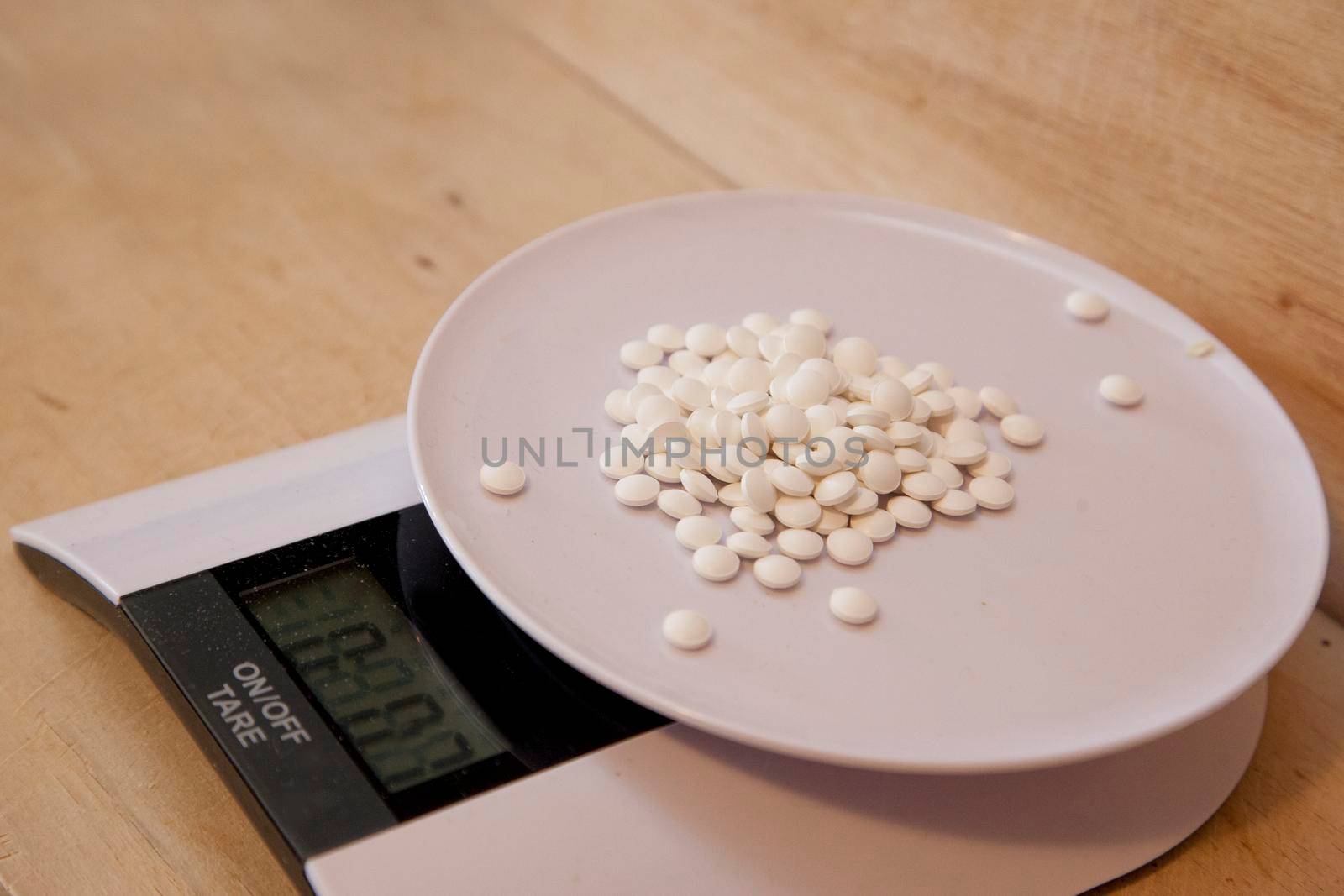 Kitchen scale with small medication or pills or vitamins being weighed 