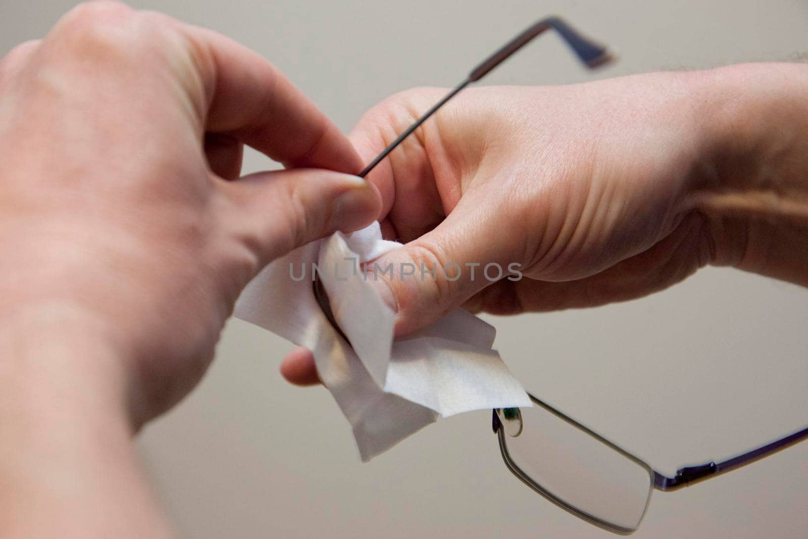 A hand uses a wipe to clean the dirt of a pair of eye glasses