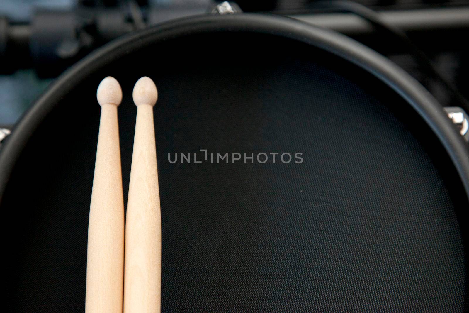  Looking down on a black electronic drum with two sticks ready to be played 