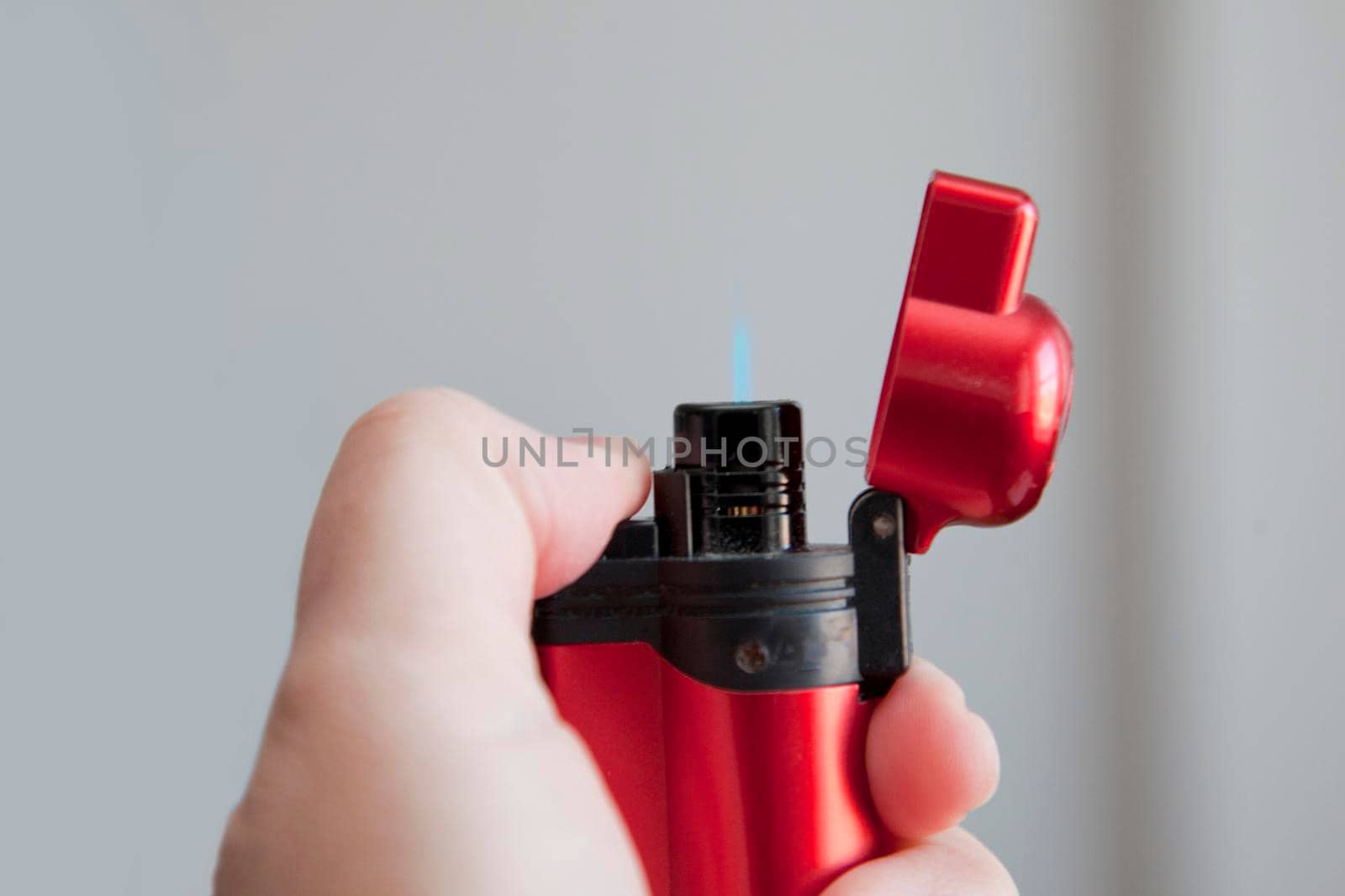 Thumb presses and lights a red butane lighter with copy space