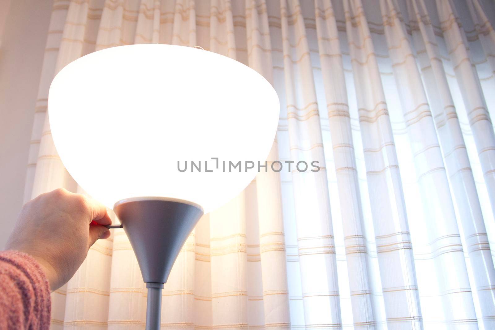 Hand turns the switch on a lamp 