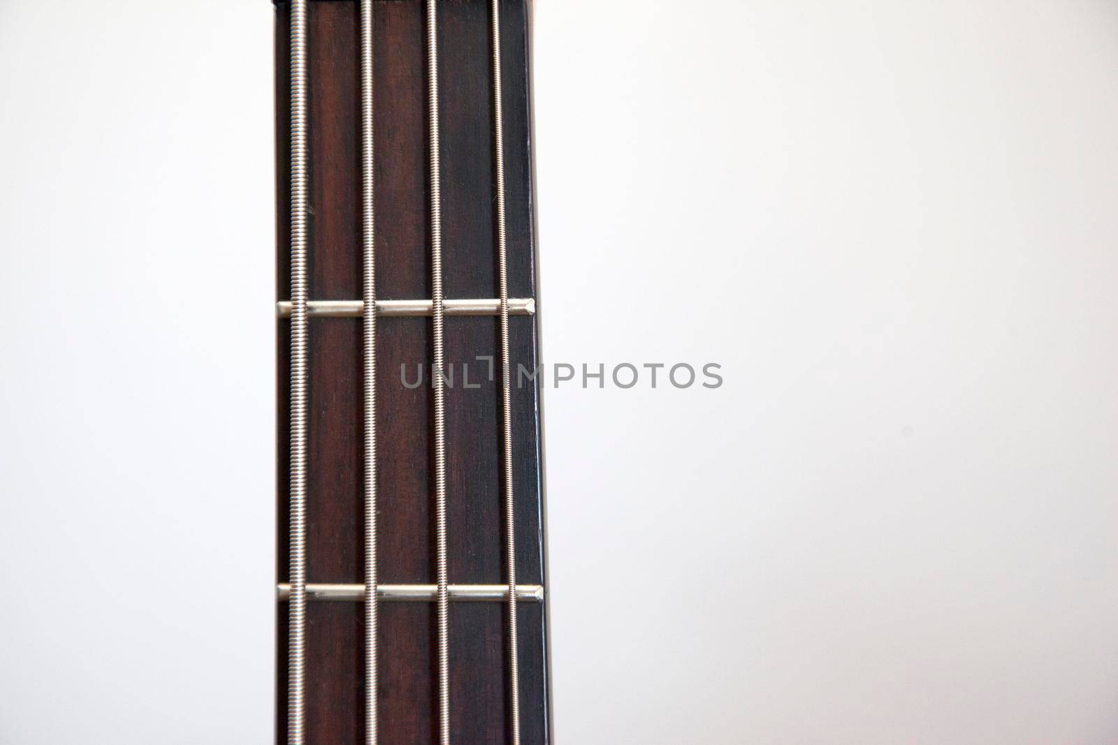 The neck of a bass guitar against white copy space 