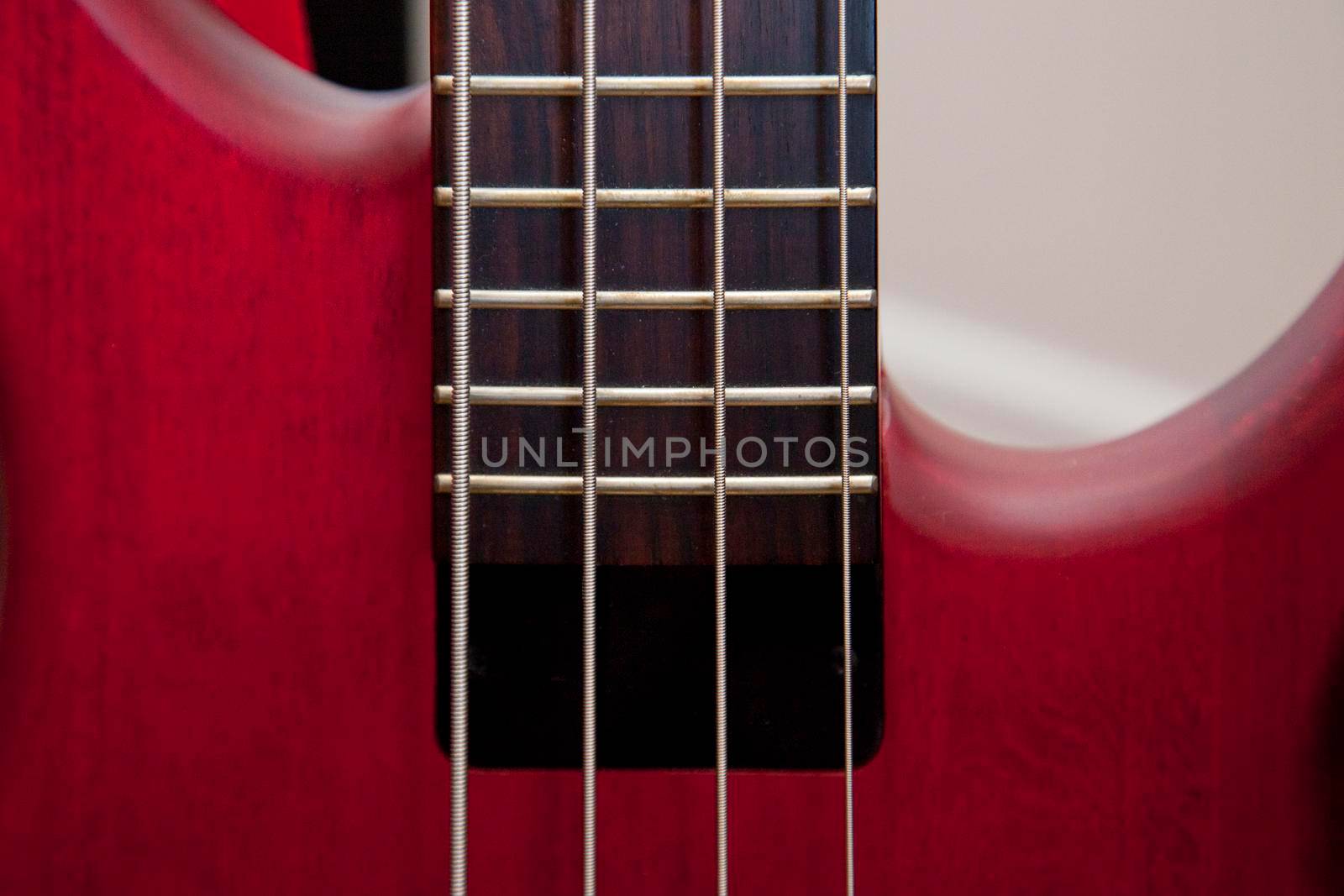  Bass guitar strings and frets on a beautiful red instrument