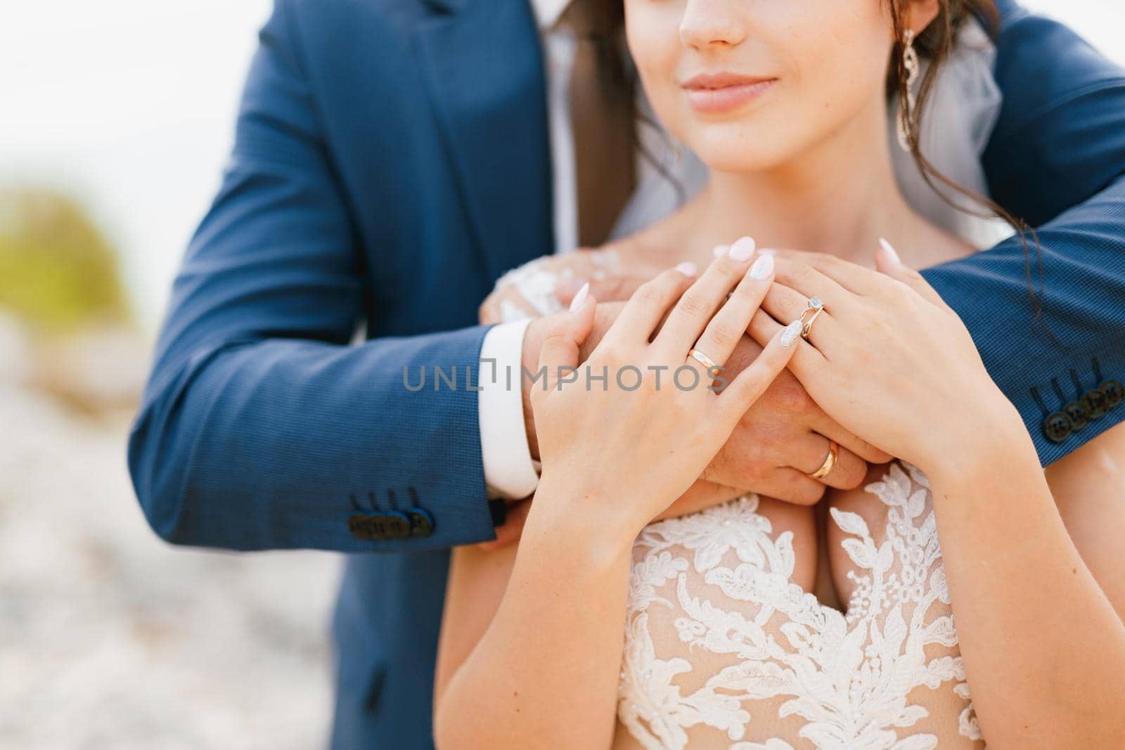 The groom gently hugs the bride by the shoulders, the bride put her hands on the groom's arms, close-up by Nadtochiy