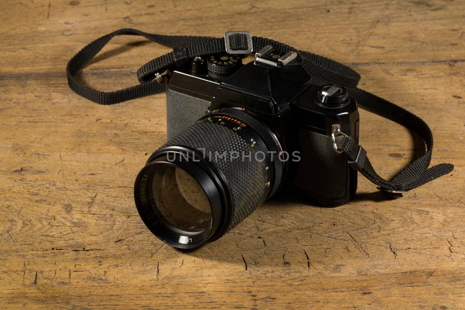 Old black retro style photo camera on a wooden table