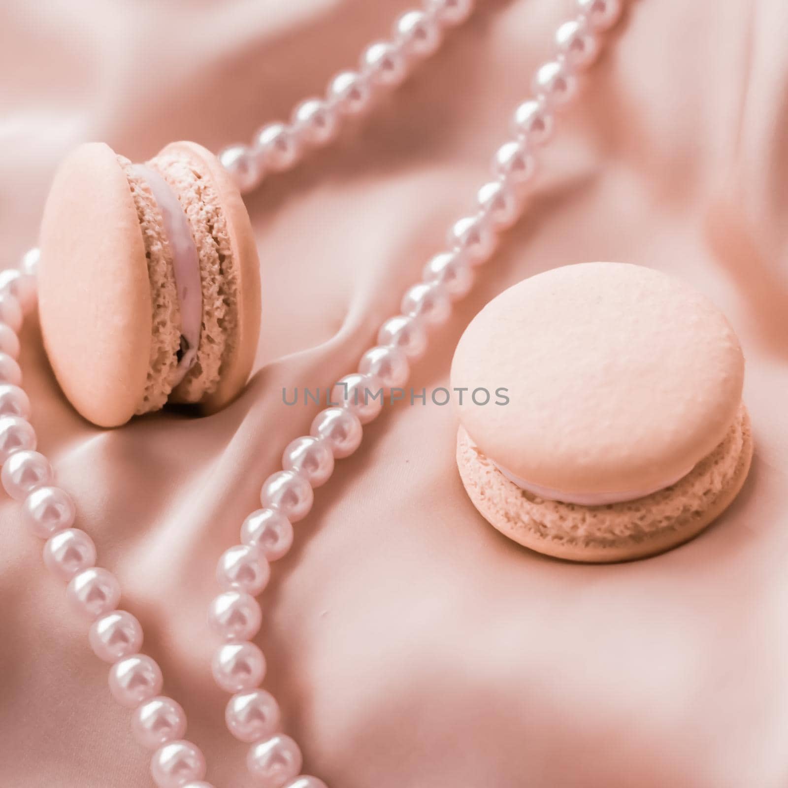 Sweet macaroons and pearls jewellery on silk background, parisian chic jewelry, French dessert food and cake macaron for luxury confectionery brand, holiday gift by Anneleven