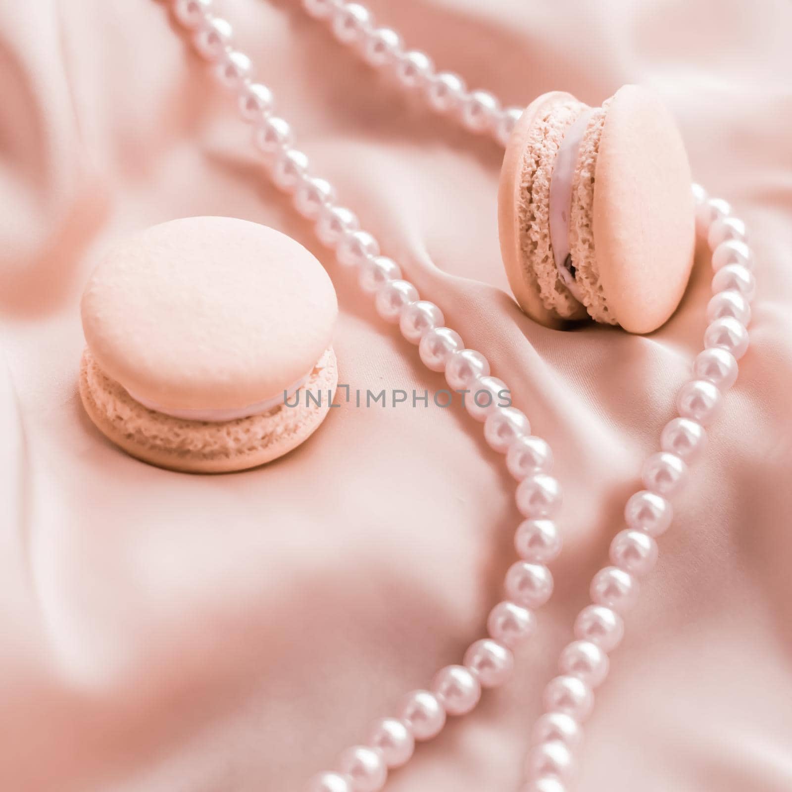 Sweet macaroons and pearls jewellery on silk background, parisian chic jewelry, French dessert food and cake macaron for luxury confectionery brand, holiday gift by Anneleven