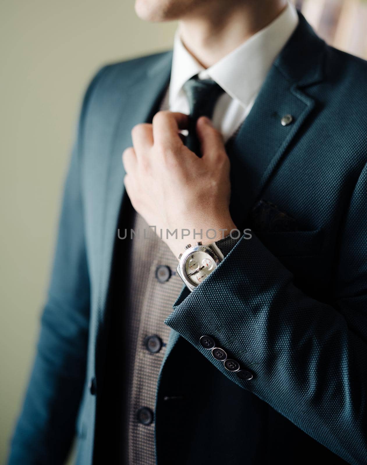 Groom straightens his tie around his neck before leaving the house. High quality photo
