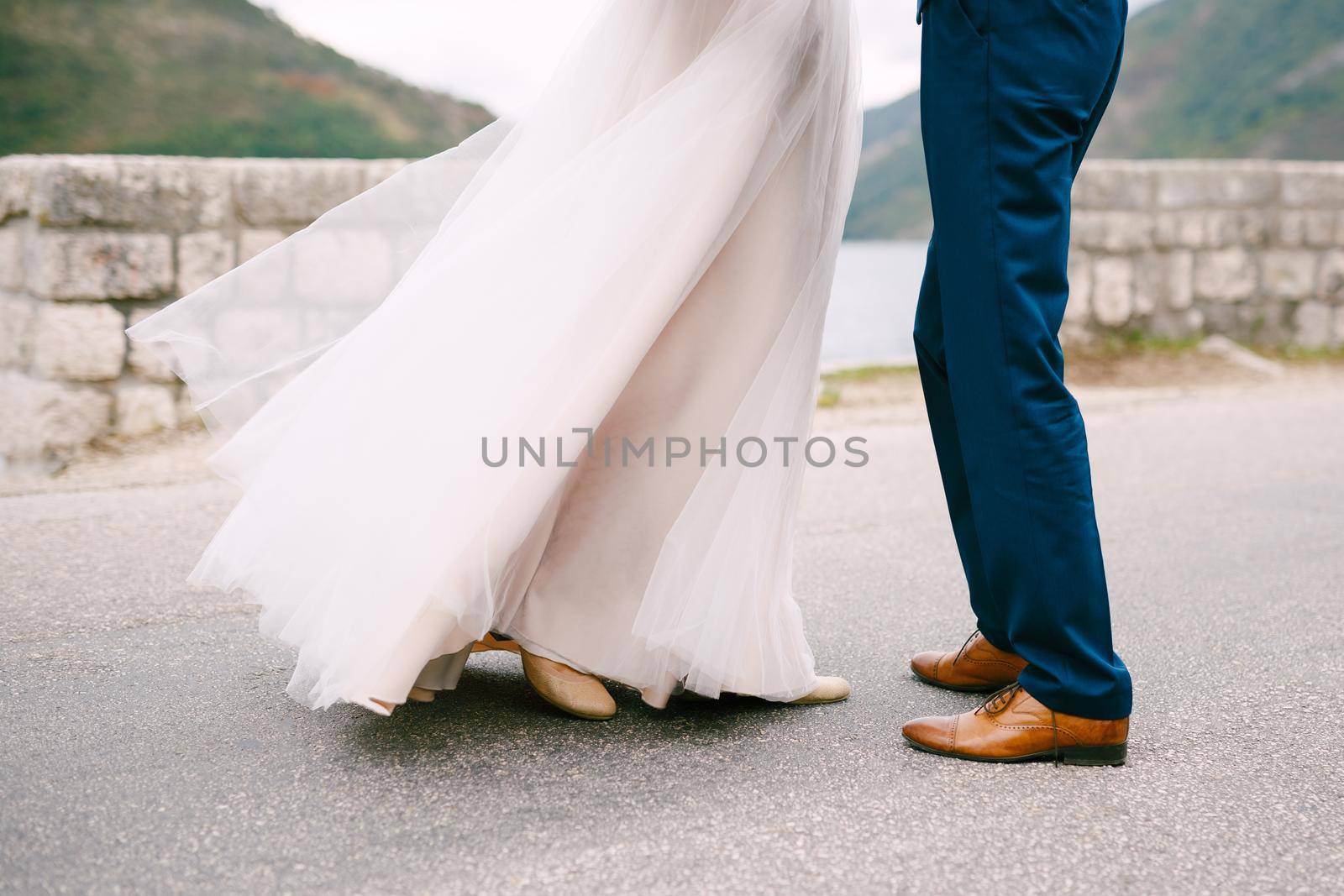 Groom and bride stand against the background of the stone wall. High quality photo