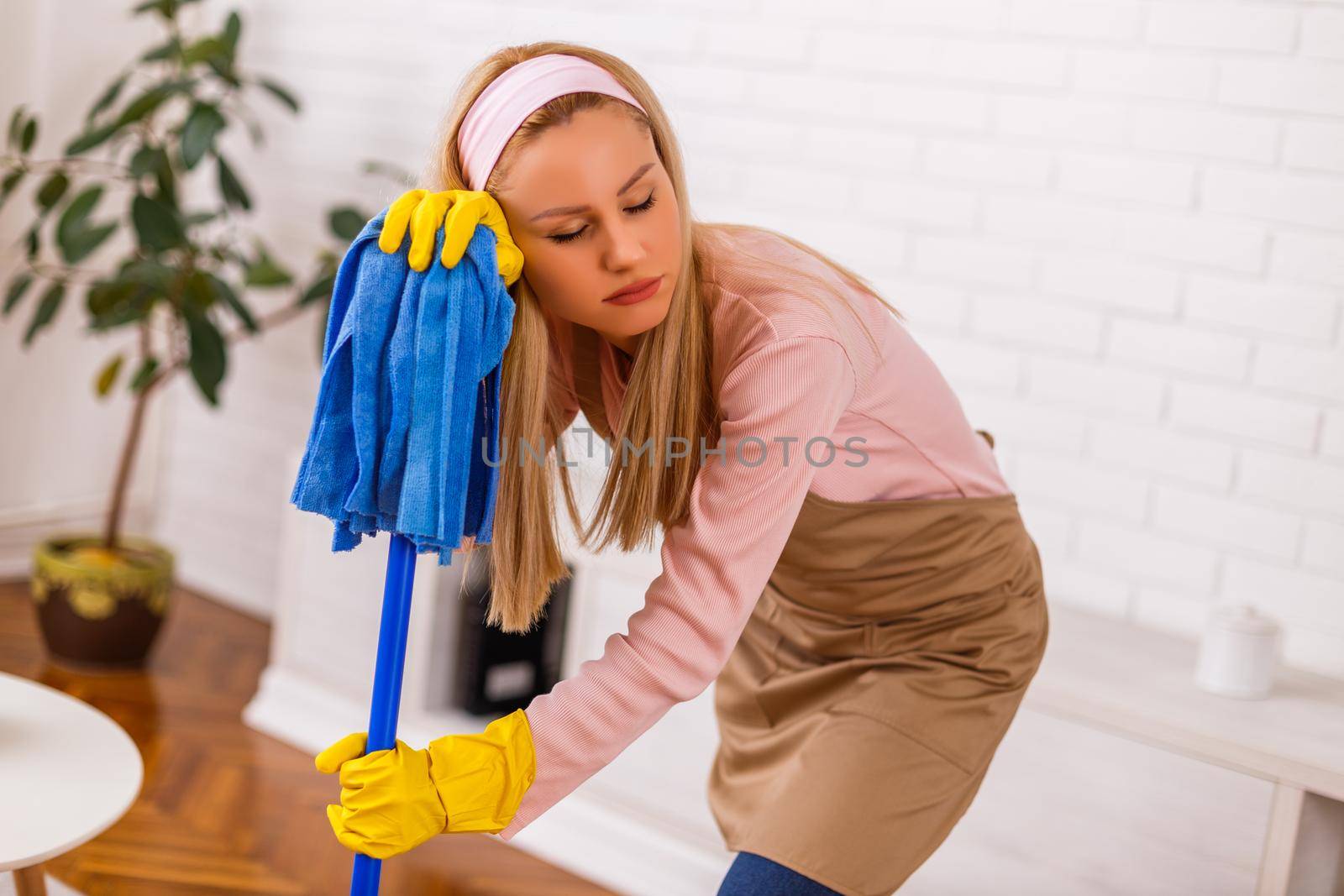 Tired housewife cleaning her home.
