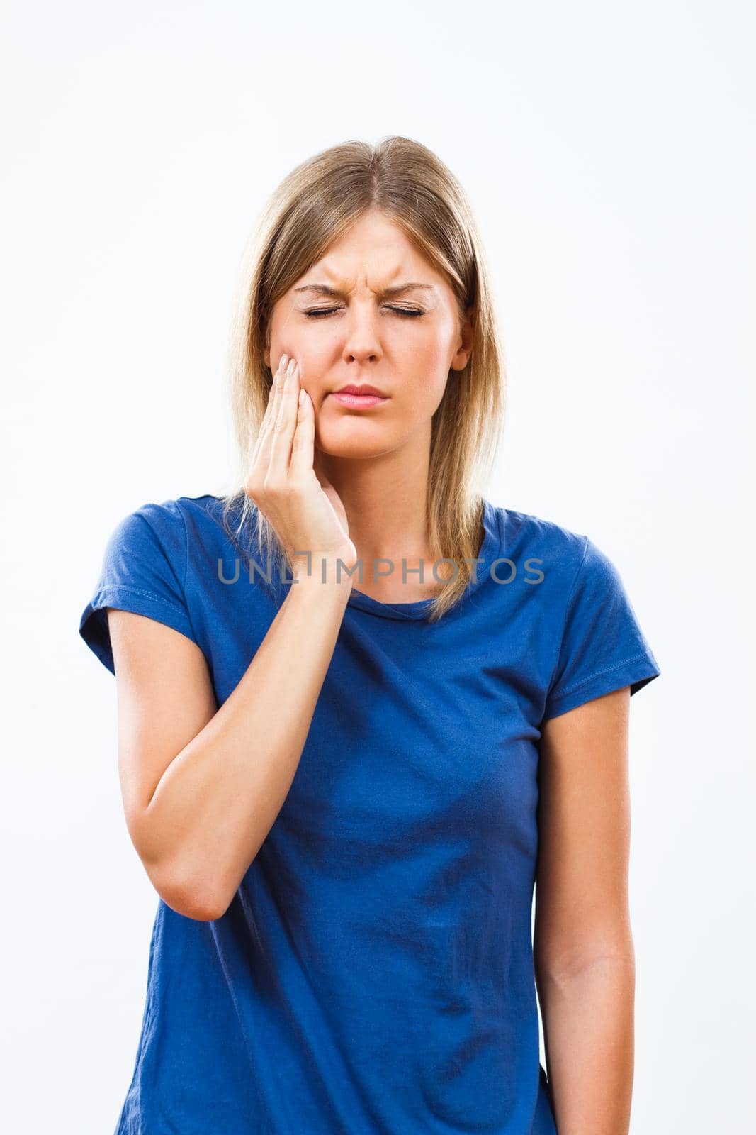 Young woman is having toothache. Touching her cheek with fingers