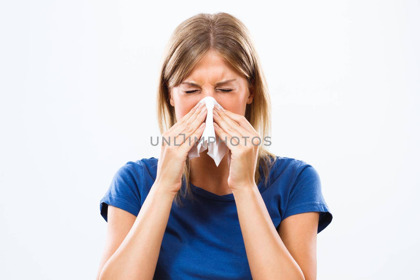 Young woman is having flu and she is blowing her nose