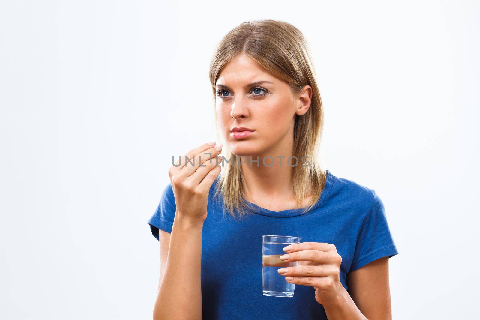 Young woman taking pill with glass of water, isolated on white