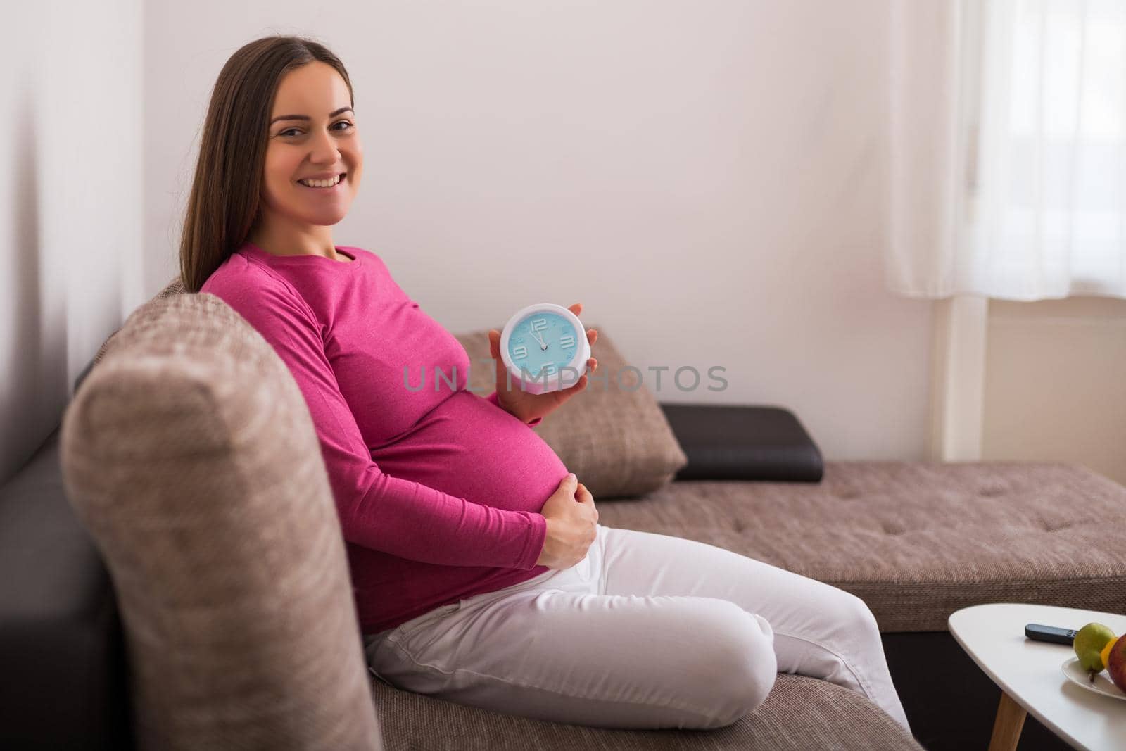 Happy pregnant woman  holding clock.