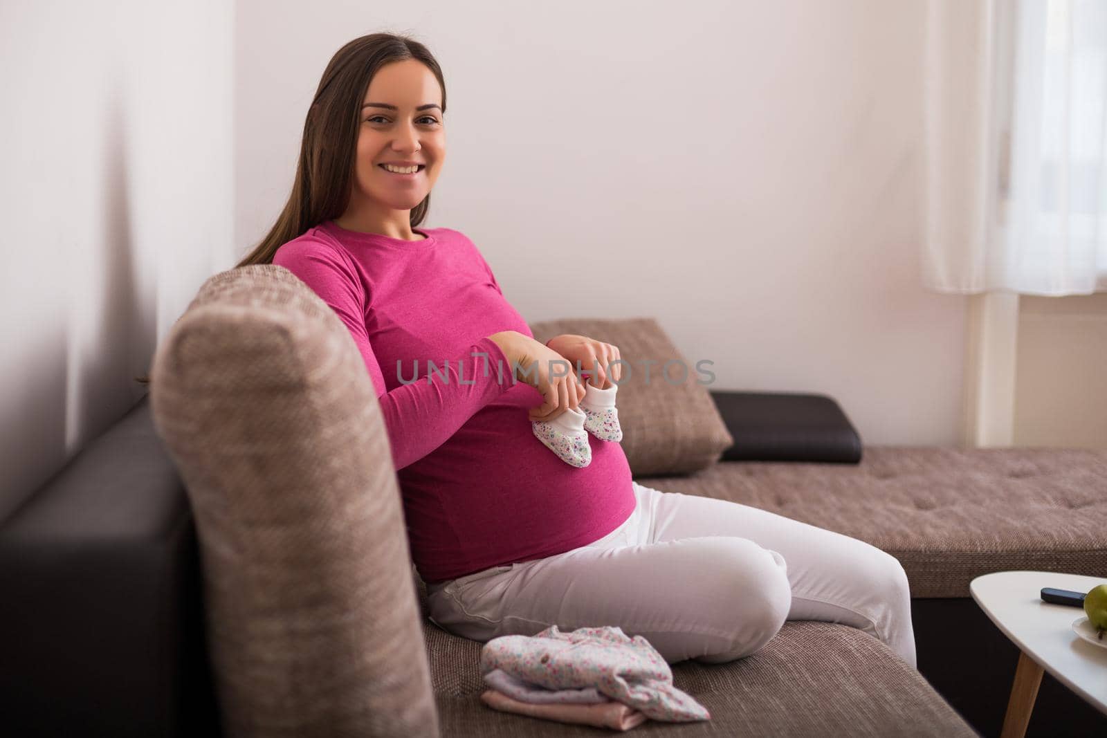 Happy pregnant woman holding little baby  socks.
