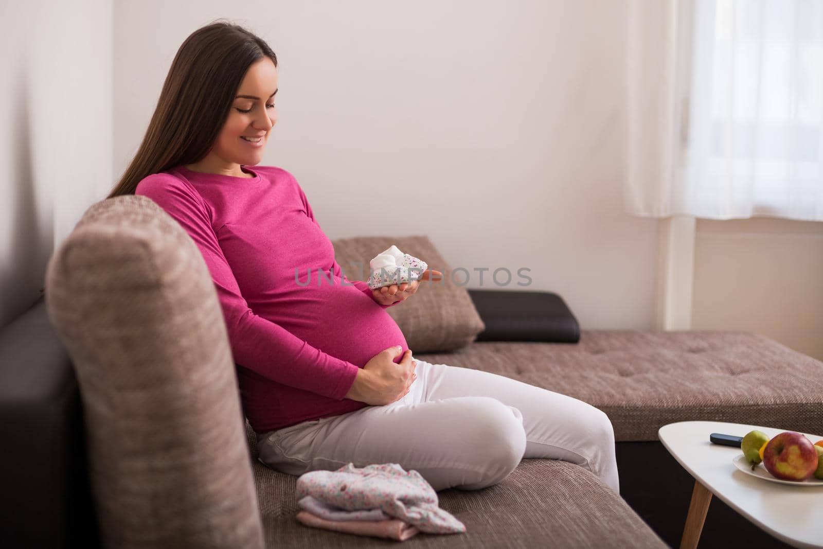 Happy pregnant woman holding little baby  socks.