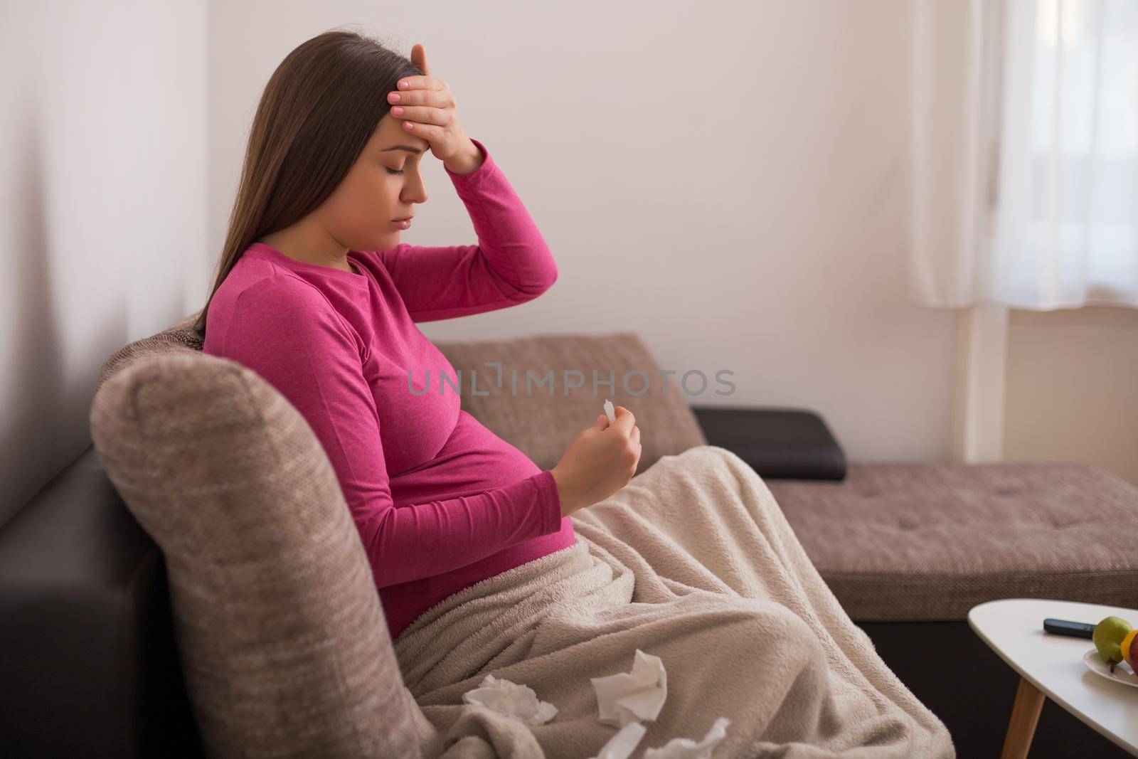 Exhausted pregnant woman having flu and checking temperature.