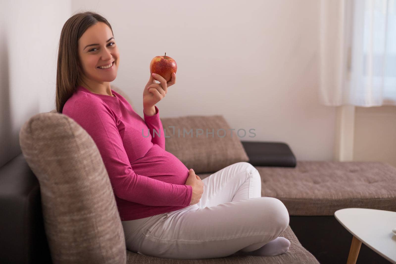 Happy pregnant woman eating apple.