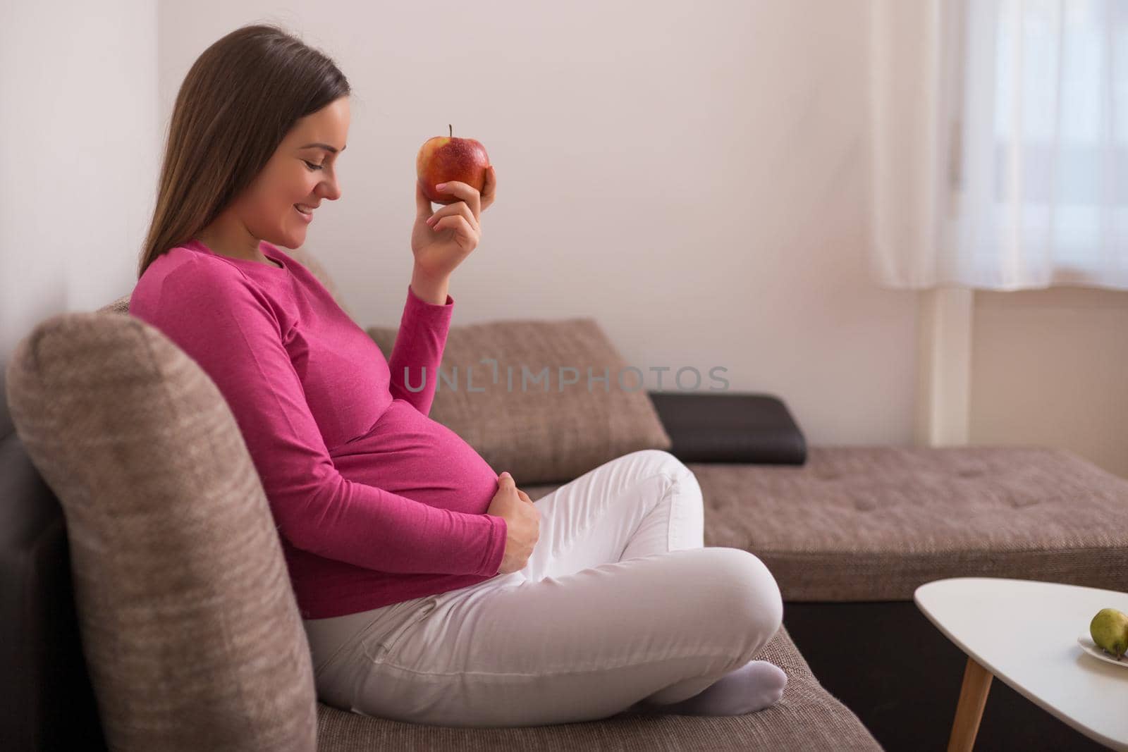 Happy pregnant woman eating apple.
