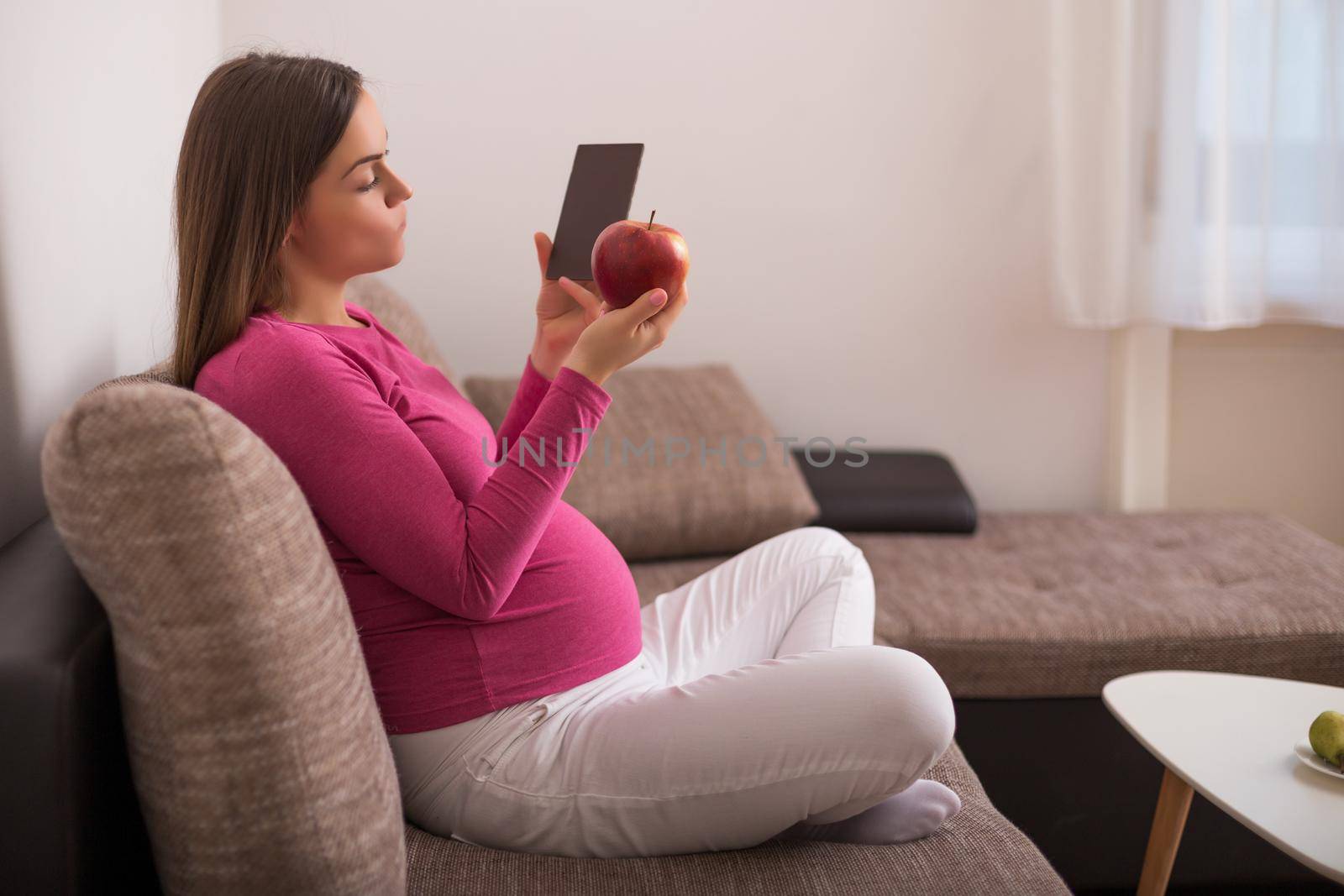 Pregnant woman is trying to decided what to eat,apple or chocolate.