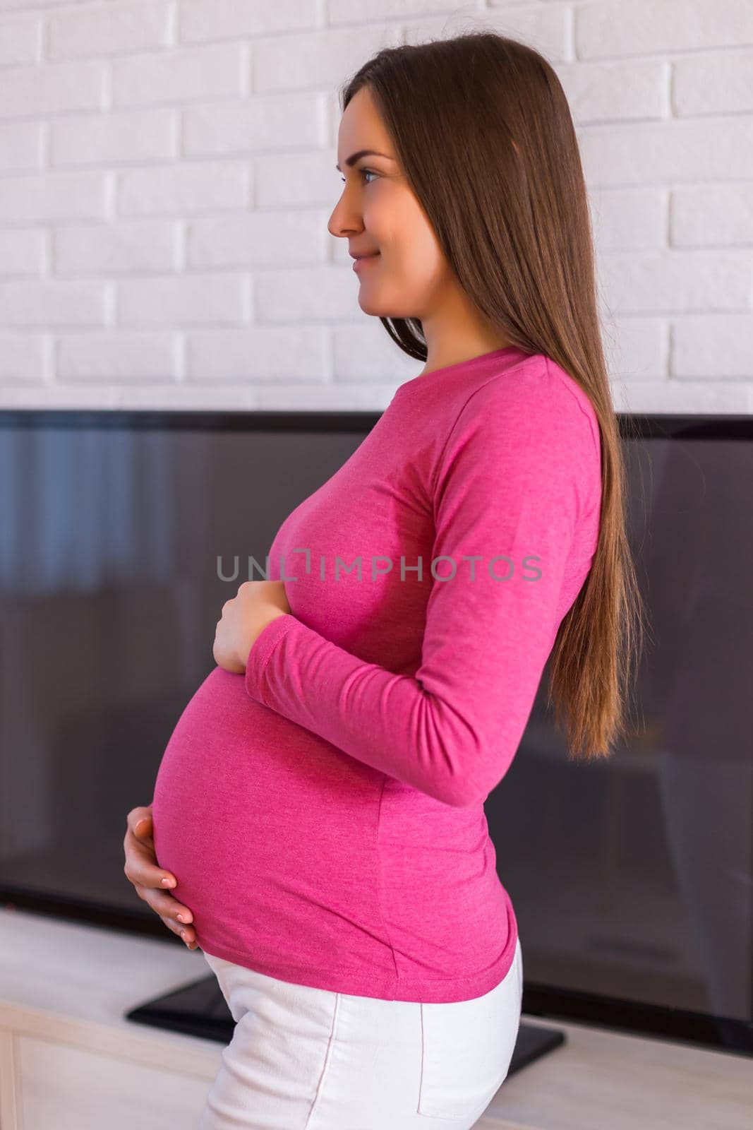 Beautiful pregnant woman enjoys spending time at her home.