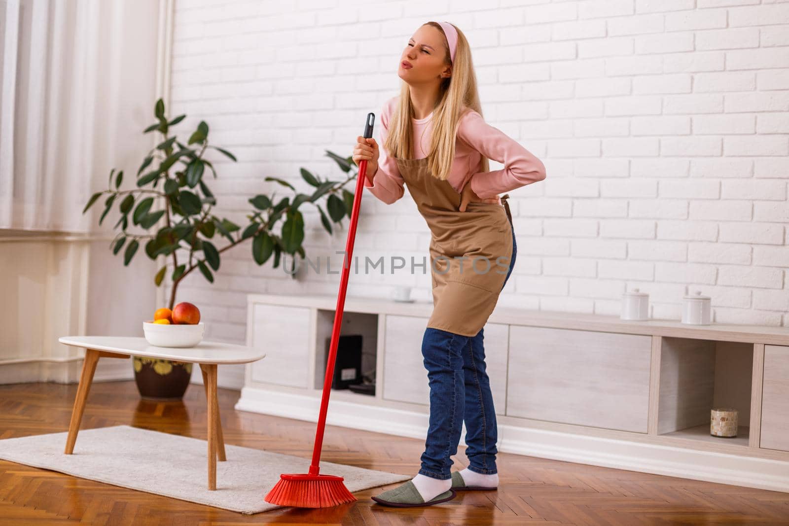 Housewife having pain in back while cleaning her home.