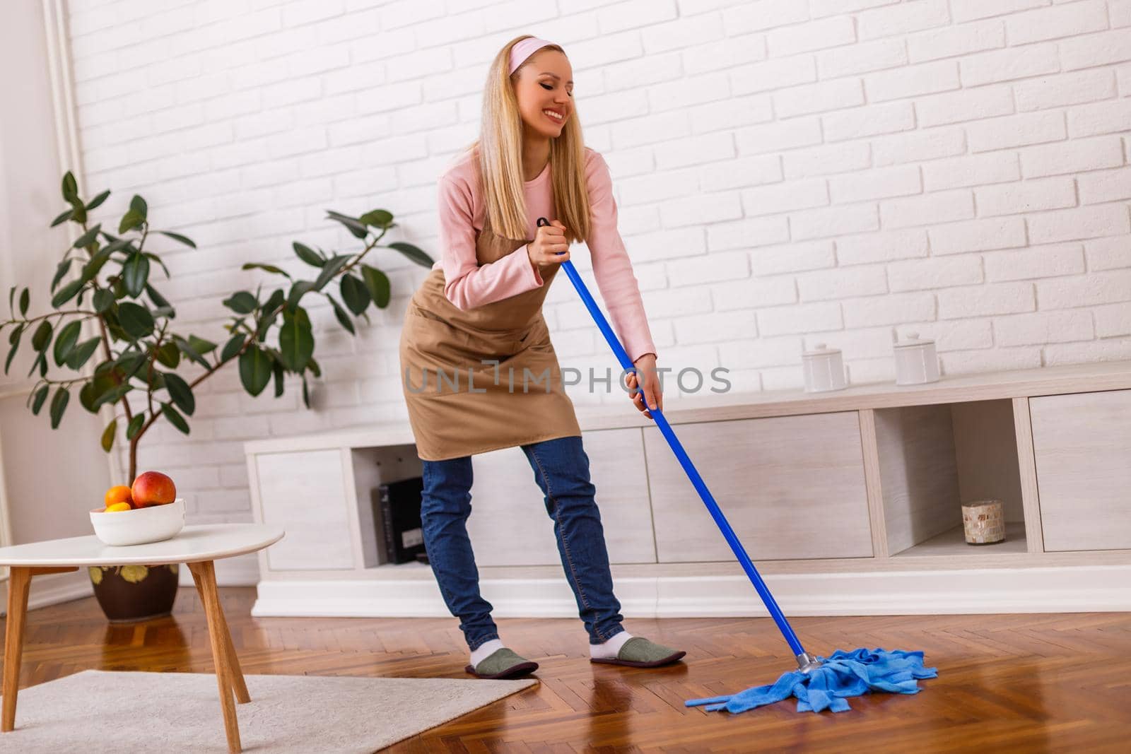 Beautiful housewife enjoys cleaning  her home.