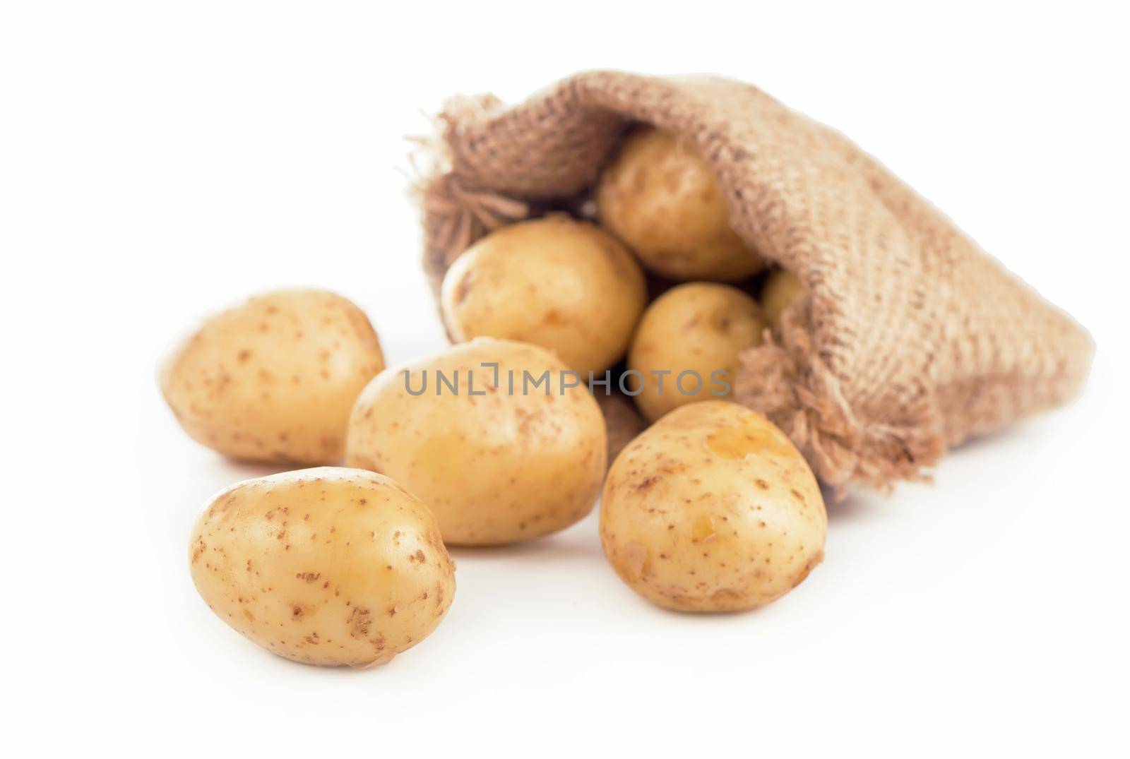 Raw potatoes in burlap bag isolated on white background by aprilphoto