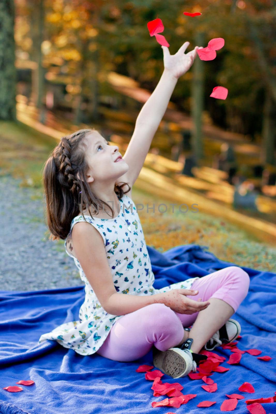 little girl throws rose petals joyfully in the air