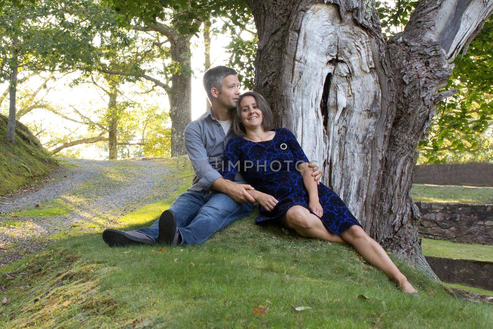 man and woman relax and smile under a big oak tree 