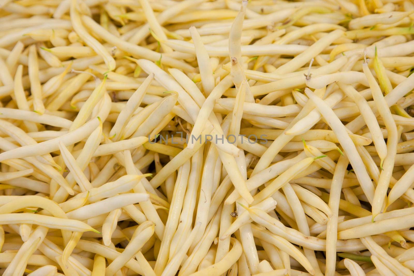 a group of yellow waxy string beans at a market