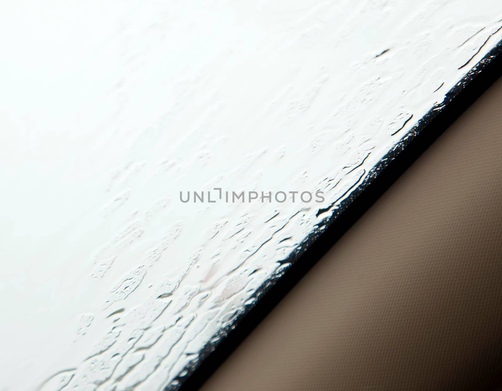 texture or background of rain on a car window with beige roll bar 