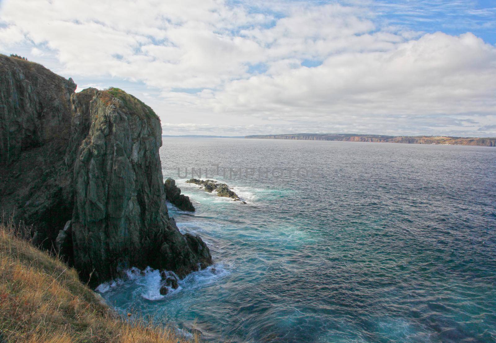 blue green waves crash against a cliffside on the east coast of canada in newfoundland