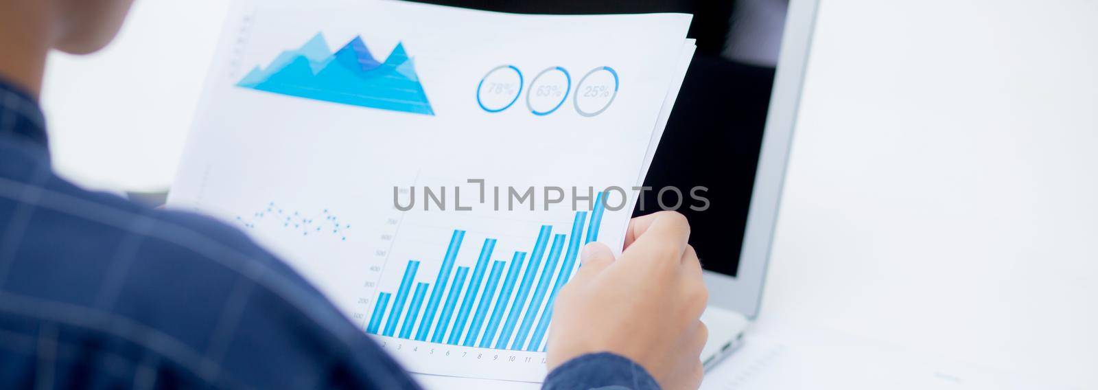 Hand of young business man looking document data graph and chart paper, marketing and investment, report of statistics profit for financial, economic and growth of finance, management and planning. by nnudoo