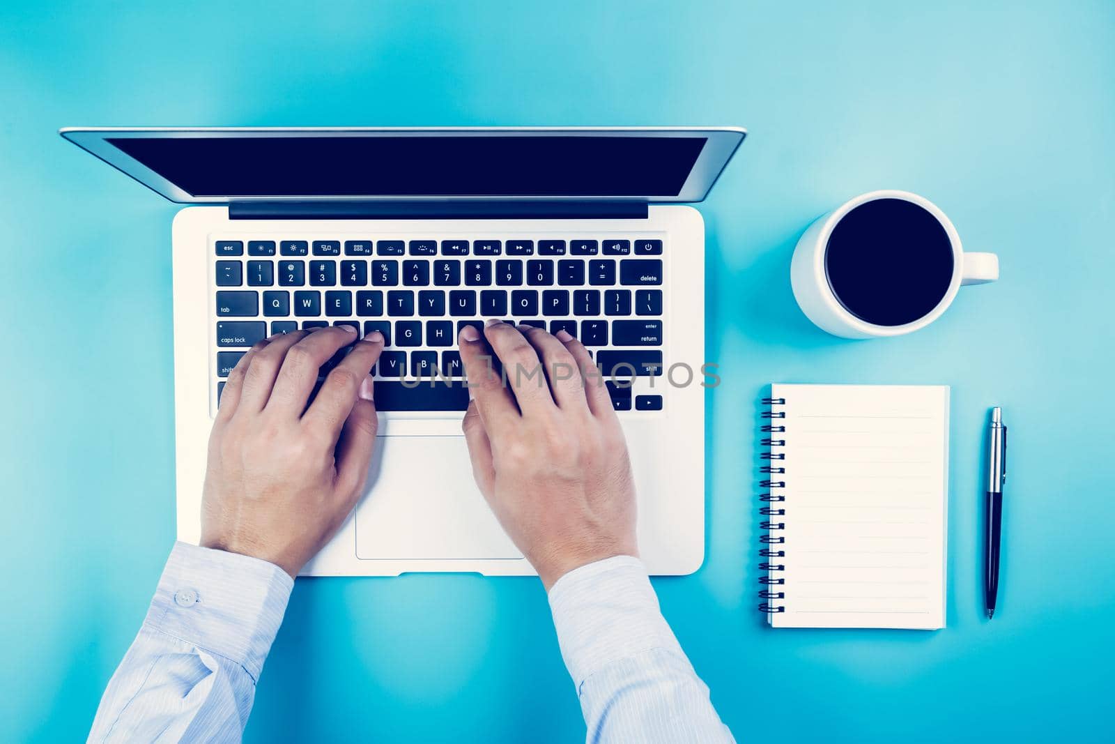 Flat lay, hand of businessman working on laptop computer with cup of coffee on desk in office, workplace and notebook and book on blue background, workspace and copy space, top view, business concept.