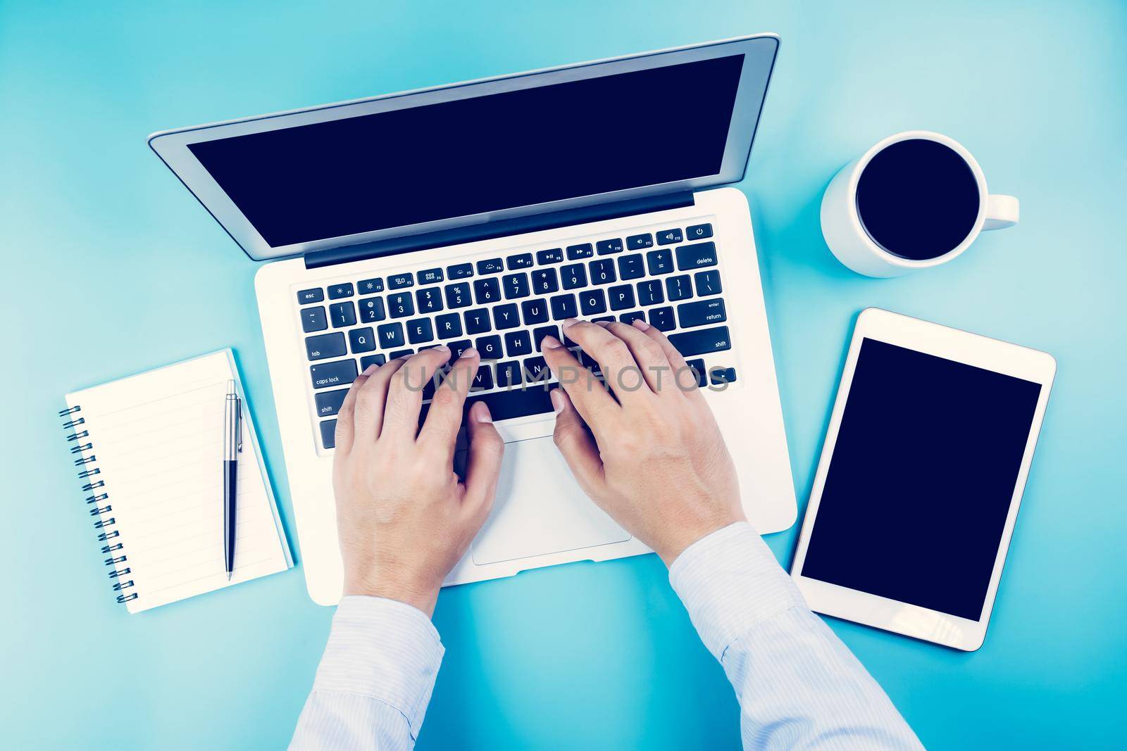 Hand of businessman working on laptop computer with tablet and notebook on desk in office, hand typing keyboard with book and pen, workplace with copy space, top view, flat lay, business concept. by nnudoo