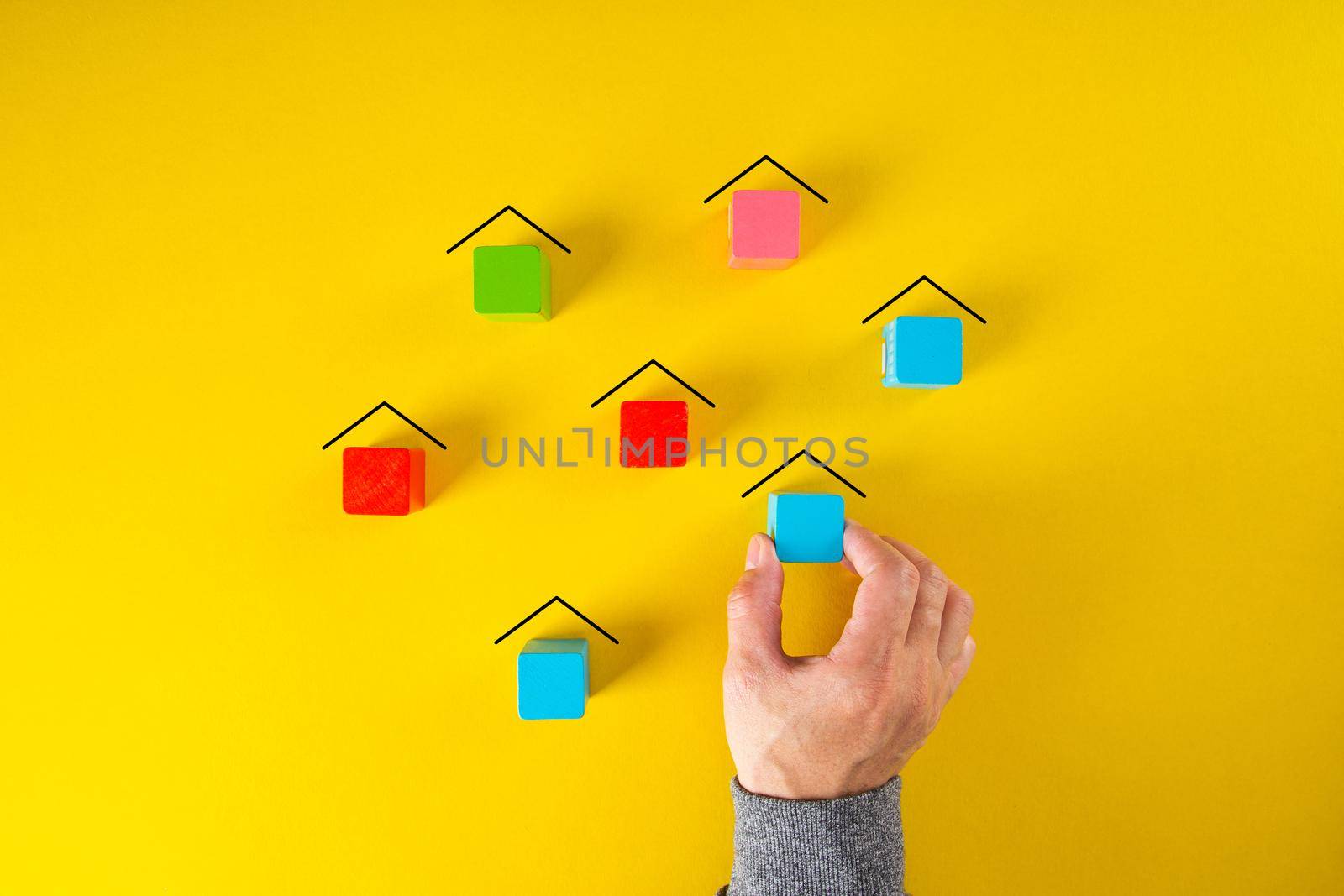 Male hand making many houses of wooden blocks in a conceptual image of urban planning and real estate.