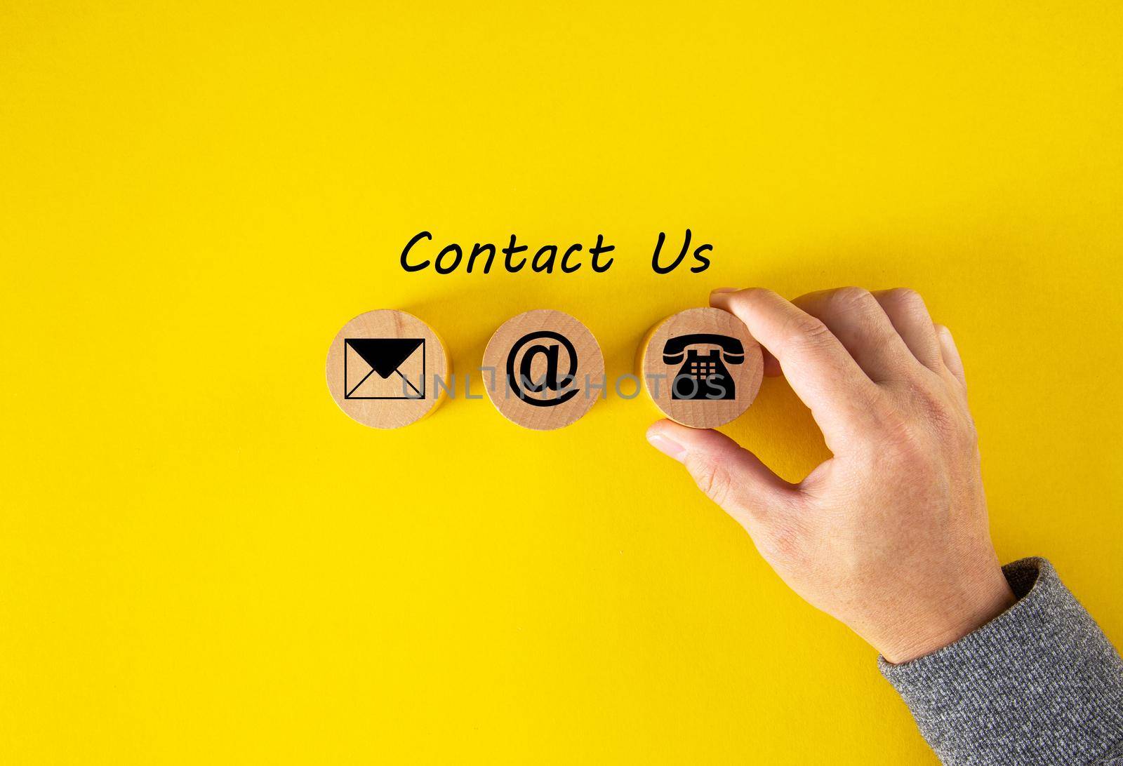 Contact Us, Customer support concept. Wooden cubes with mail, phone and email icons on table, yellow background. by tehcheesiong
