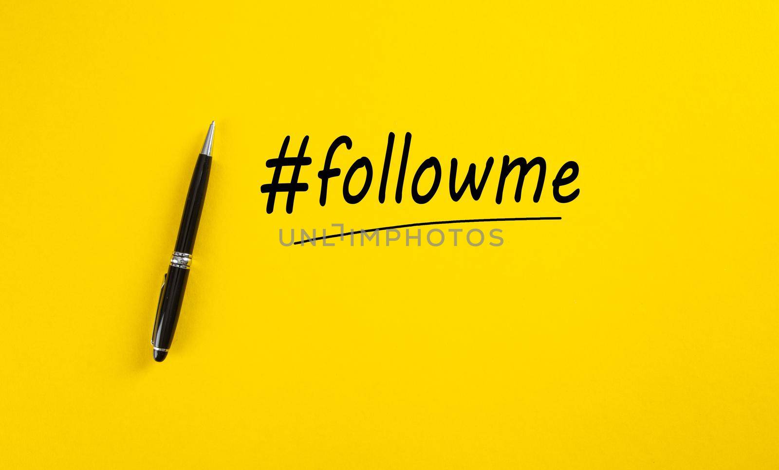 Word follow me or hashtag followme hand written with a black marker pen on yellow background.