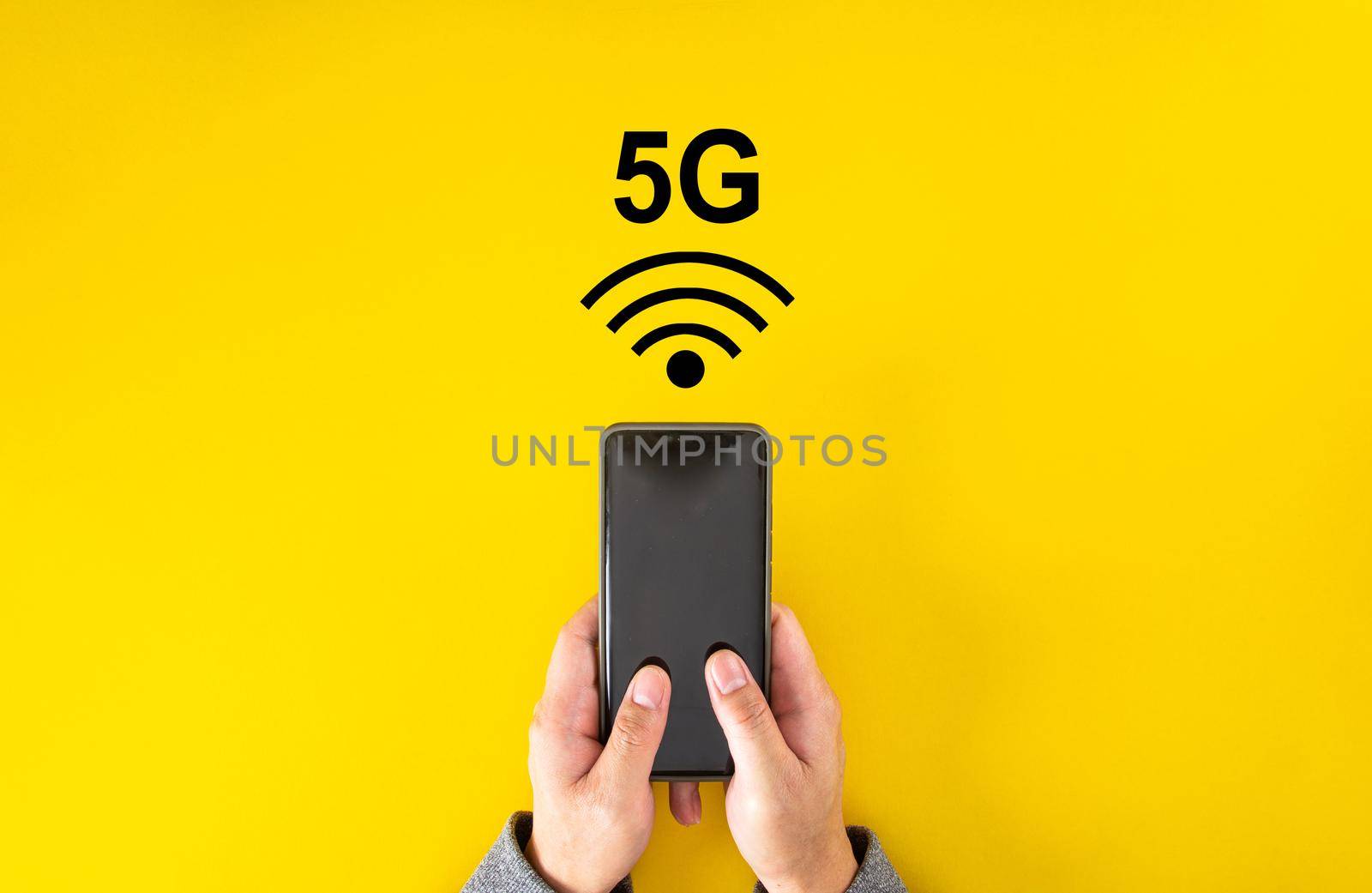 Male hand holding smartphone with 5G signal on yellow color background with copy space.