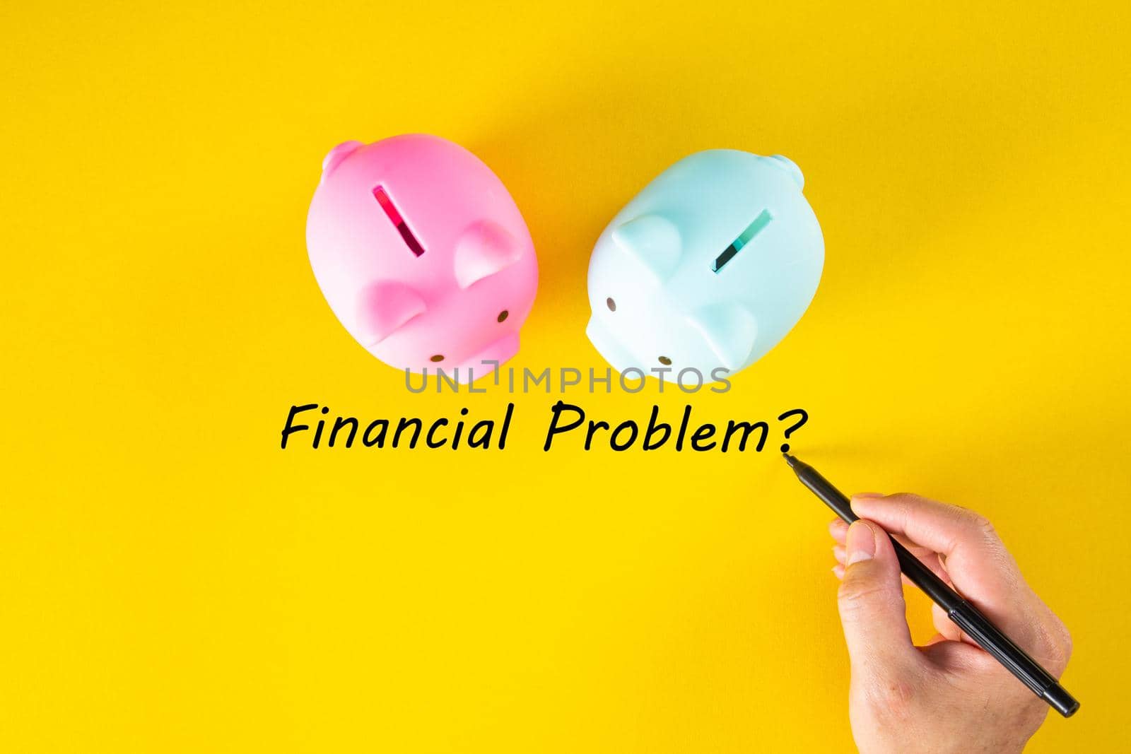A hand writes the words FINANCIAL PROBLEM on the yellow background. Business and finance concept